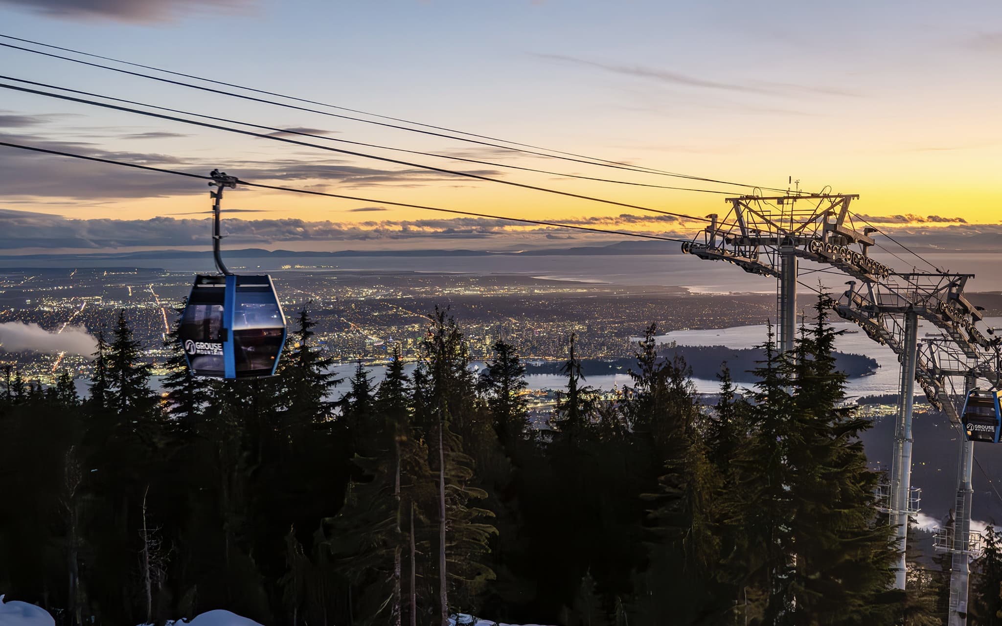 Gondola in forested mountainous area overlooking a city